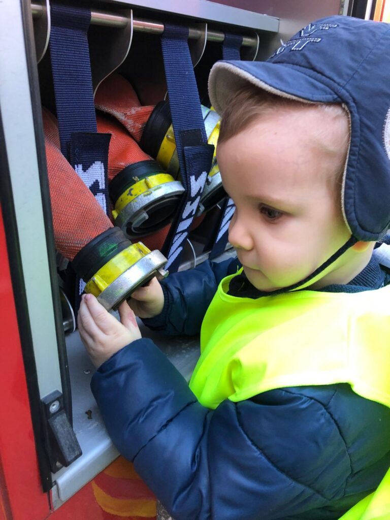 Przedszkolak dotyka węża strażackiego.