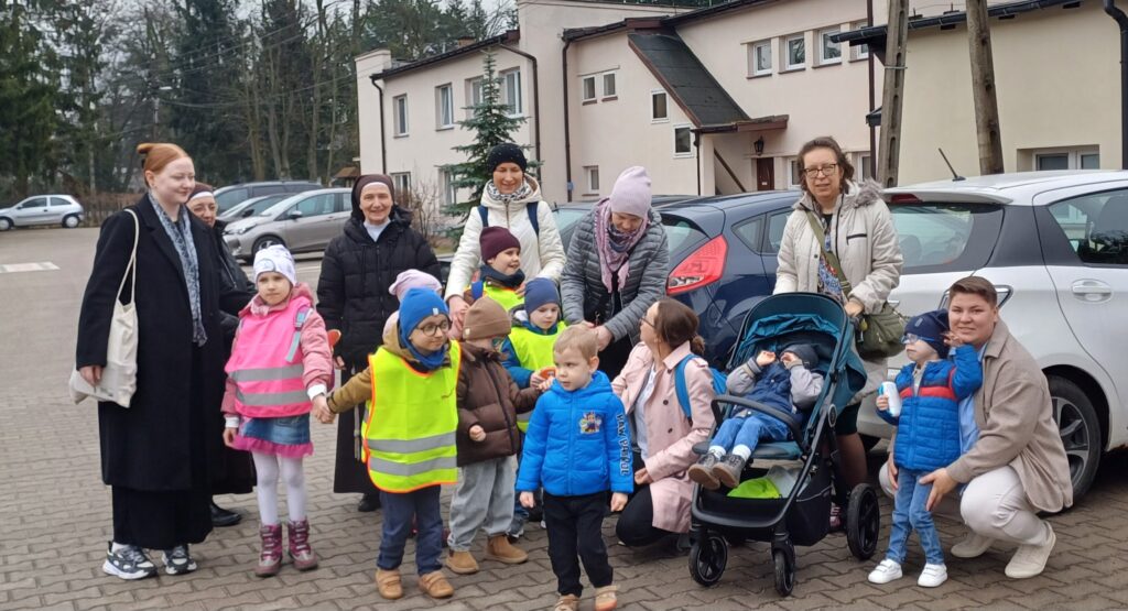 Przedszkolaki z paniami na parkingu.