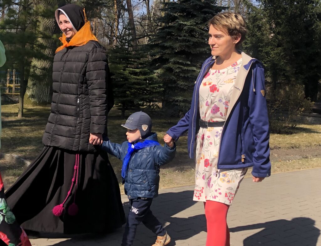 Chłopiec z paniami maszeruje chodnikiem.