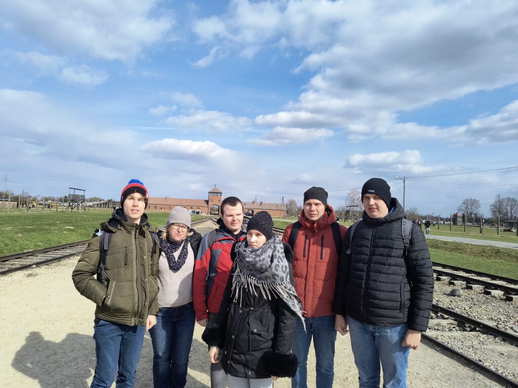 Grupa na tle bramy prowadzącej do obozu Auschwitz-Birkenau.
