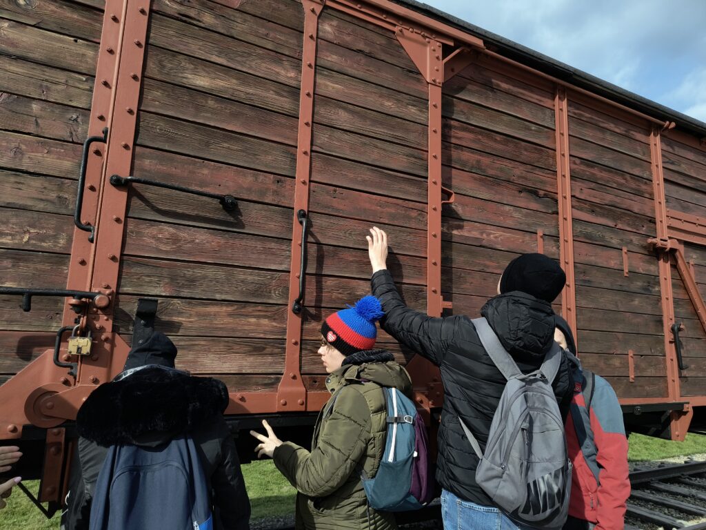 Grupa obok wagonu towarowego na terenie obozu w Brzezince