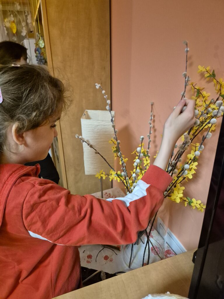 Maja W. dotyka gałązki bazi i forsycji