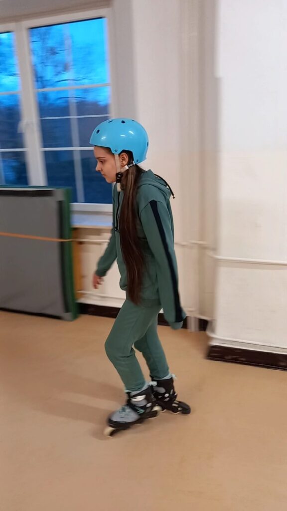 Liza jedzie na rolkach, ma na głowie kask. 