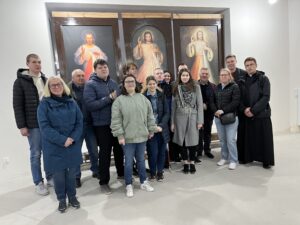Wszyscy uczestnicy pielgrzymki na tle trzech wizerunków Jezusa Miłosiernego. Pierwszy od lewej autorstwa Eugeniusza Kazimirowskiego, drugi Adolfa Hyły i trzeci Elżbiety Hoffmann - Plewy