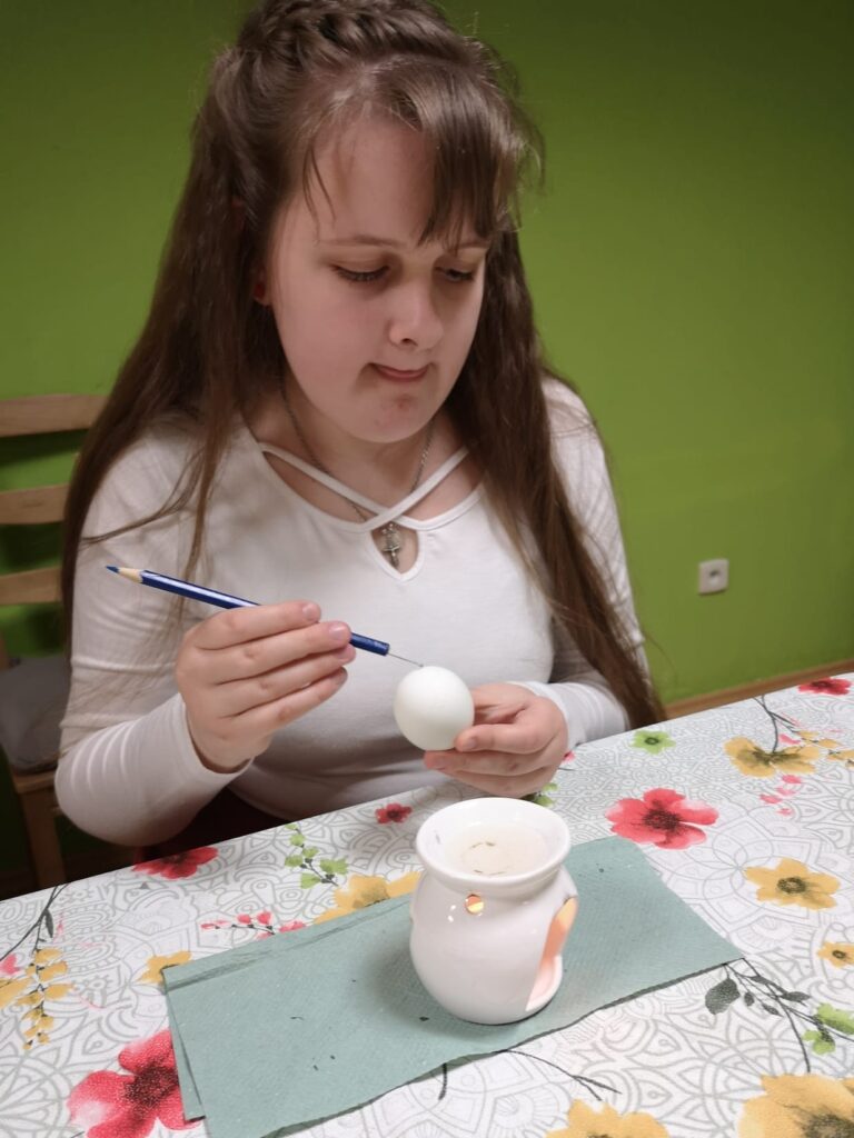 Anastazja maluje woskiem wzór na jajku