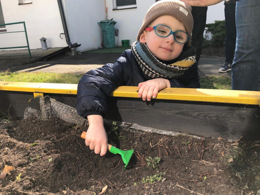 Chłopiec grabi ziemię.