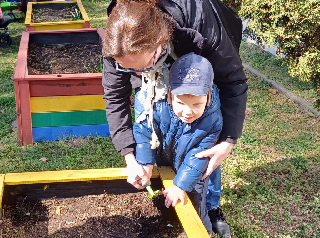 Chłopiec z nauczycielką kopie łopatką  ziemię