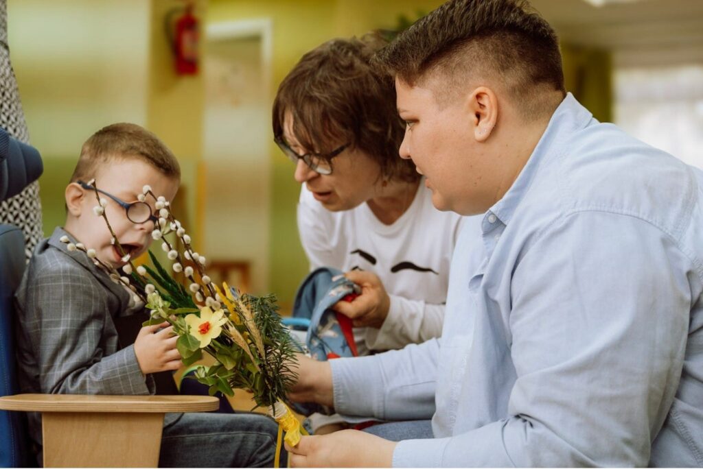 Mama i nauczycielka pokazują chłopcu zrobioną palemkę wielkanocną.