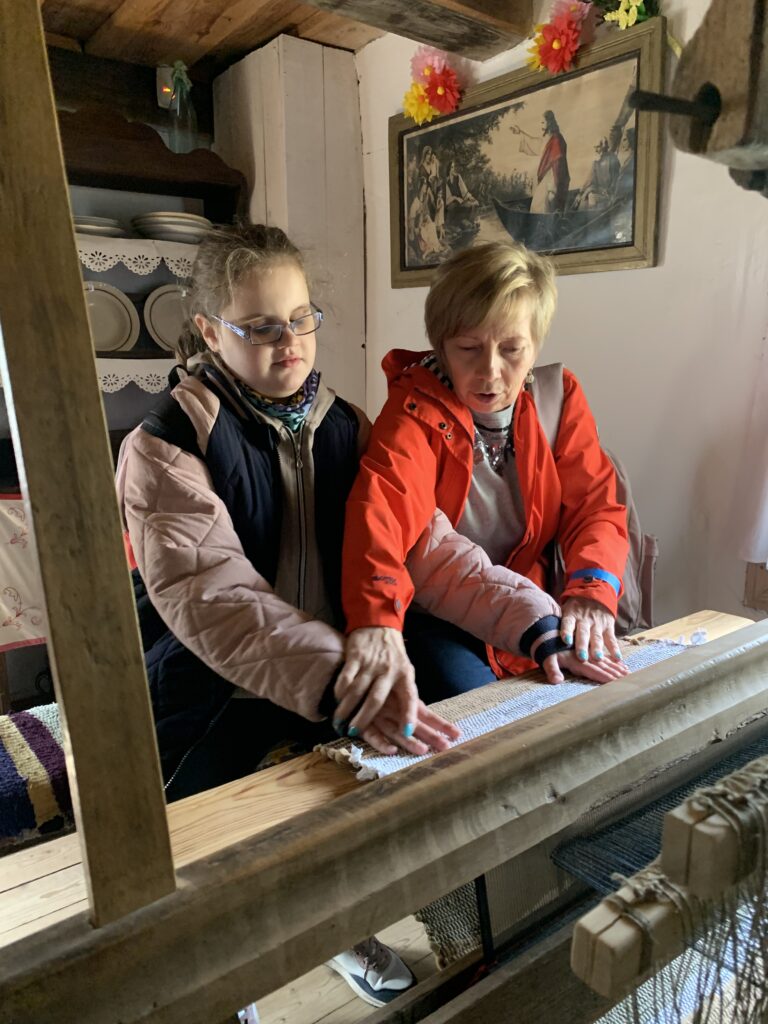 Dziewczynka z pomocą wychowawczyni ogląda materiał zrobiony na krosnach