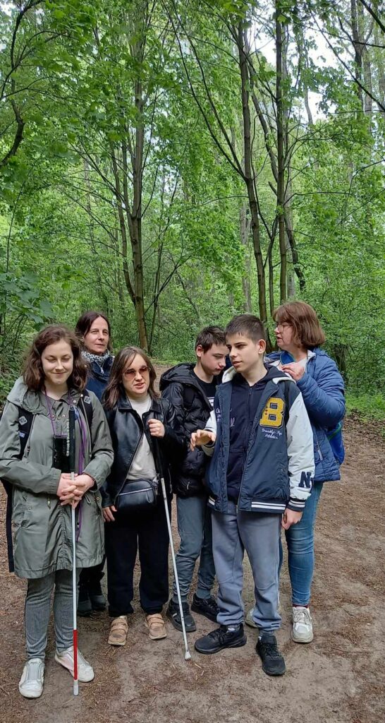 Grupka młodzieży z wychowawczyniami na tle lasu