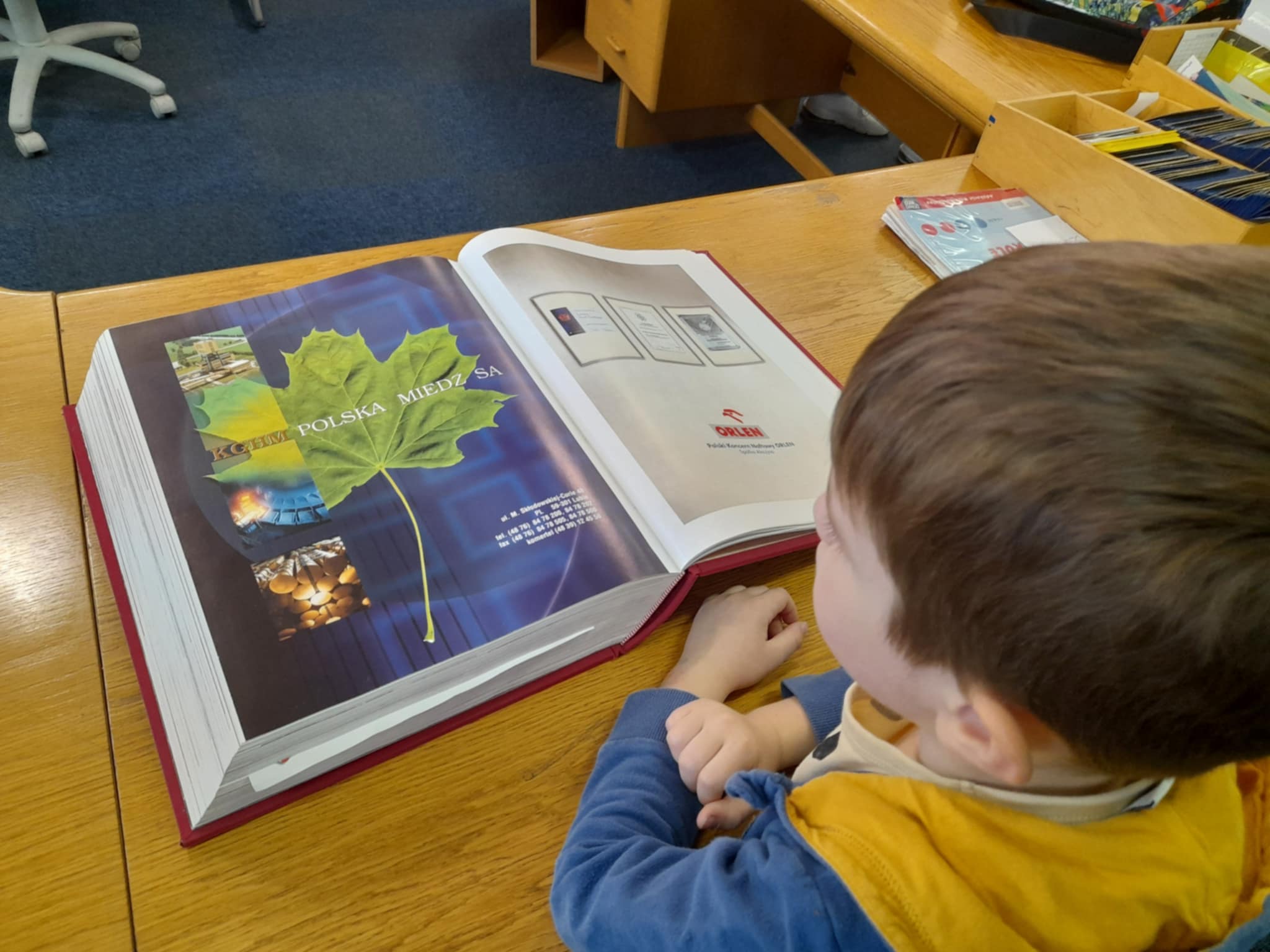 chłopiec z książką siedzący przy stoliku