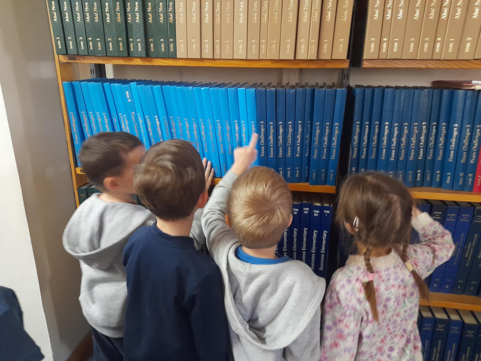 przedszkolaki oglądający regał z książkami