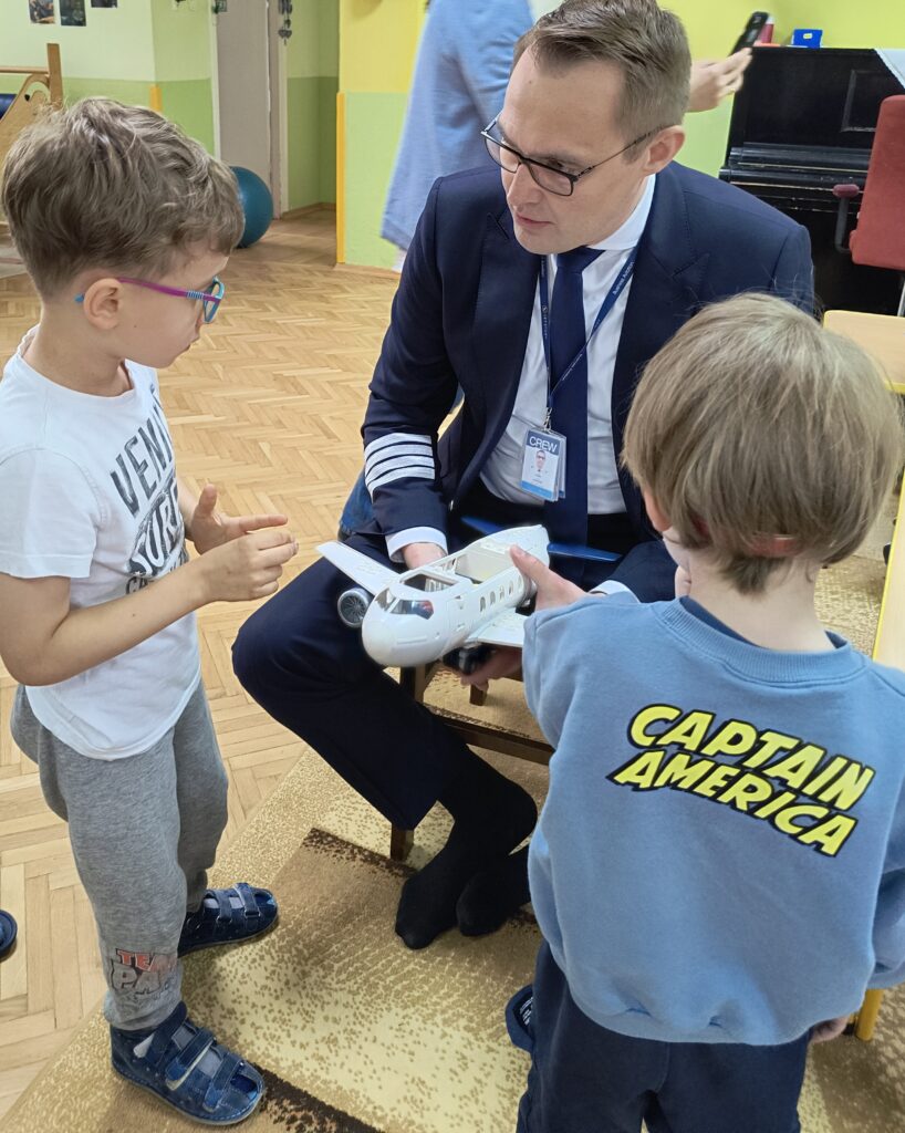 Dwaj chłopcy i pan pilot trzymający zabawkowy samolot ,