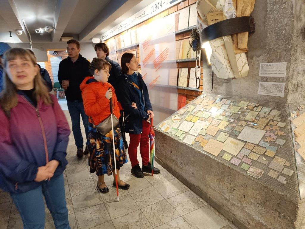     Zapytanie zostało przetworzone

Widoczna na zdjęciu grupa osób kontynuuje swoją wycieczkę, tym razem zwiedzając wnętrze muzeum. Skupiają się wokół gabloty z eksponatami, najprawdopodobniej dokumentami lub pamiątkami, które są związane z historią miejsca i postacią Błogosławionego Księdza Jerzego Popiełuszki. Ściana za nimi jest pokryta grafikami i tekstem.