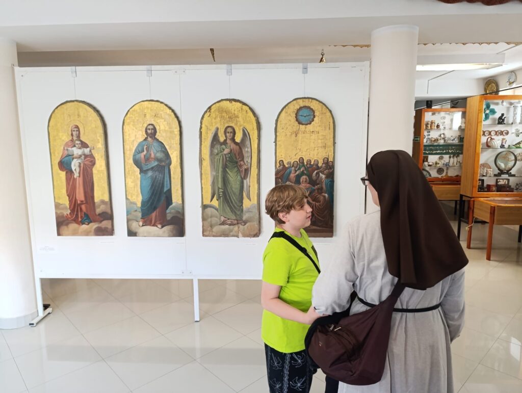 Uczeń z siostrą zakonną stoją obok ikon