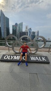 Alex przy pomniku w kształcie kół olimpijskich