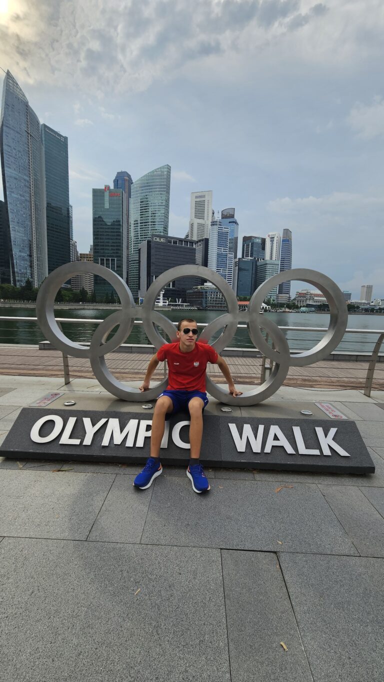Alex przy pomniku w kształcie kół olimpijskich