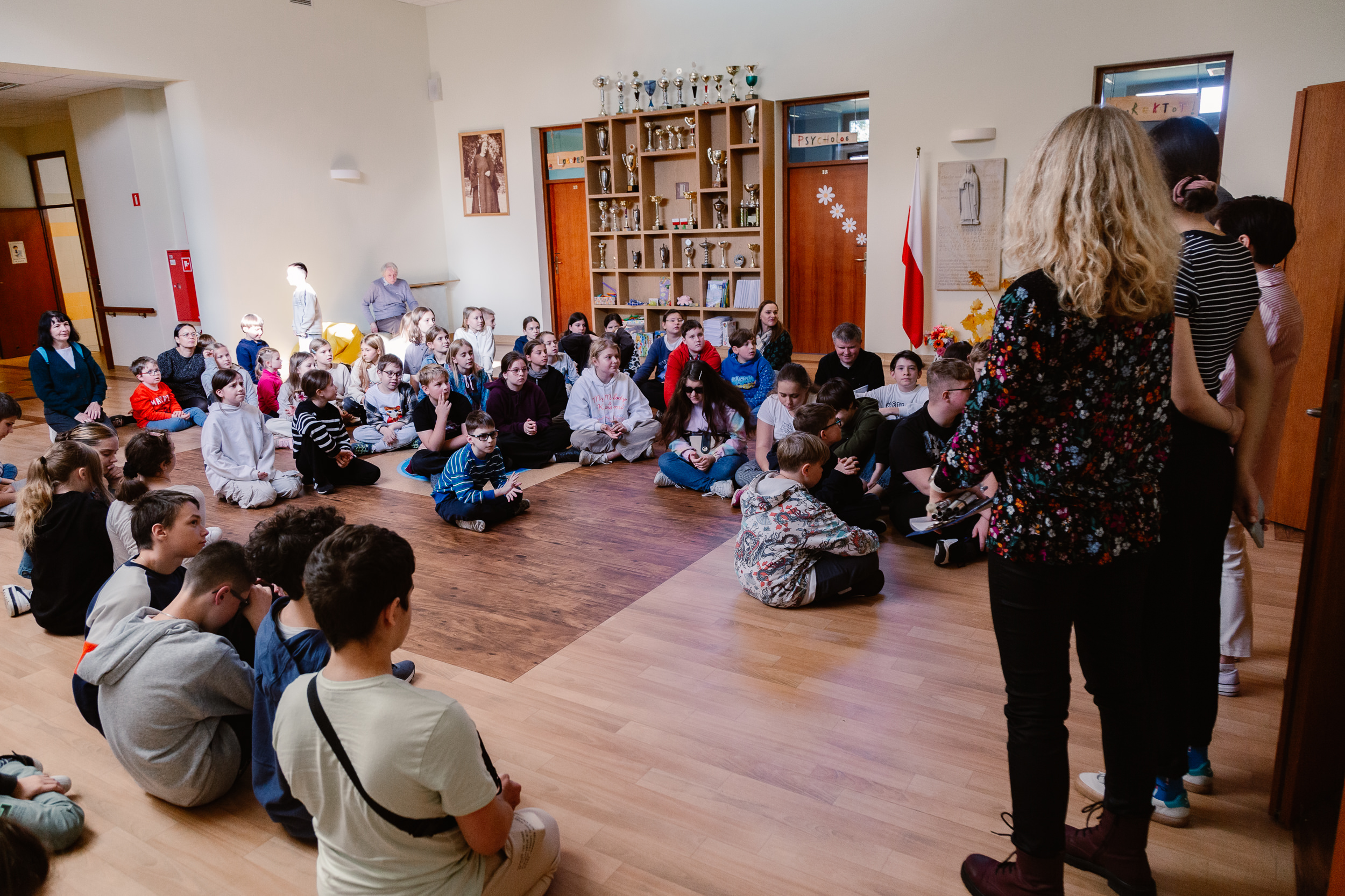 Uczniowie zebrani w holu szkoły podstawowej.