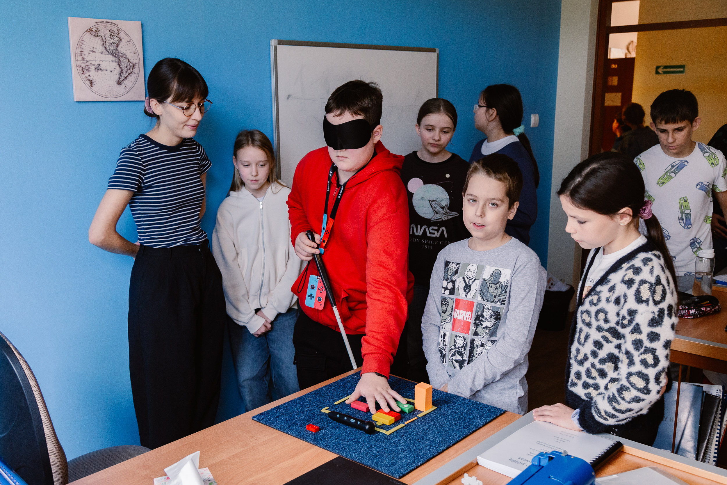 Chłopiec z opaską na oczach ogląda klocki na biurku