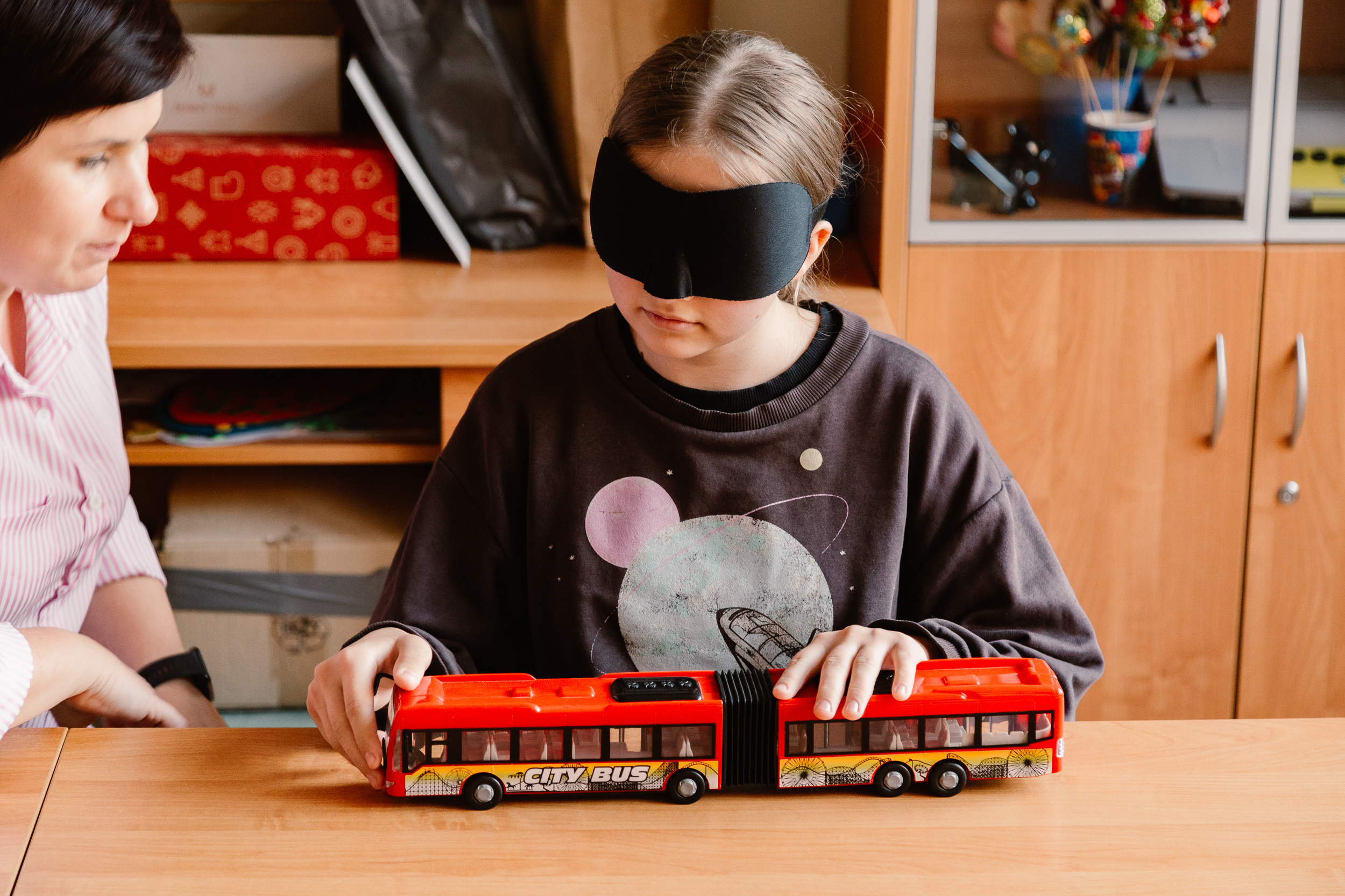 Dziewczynka z opaską na oczach ogląda model pojazdu