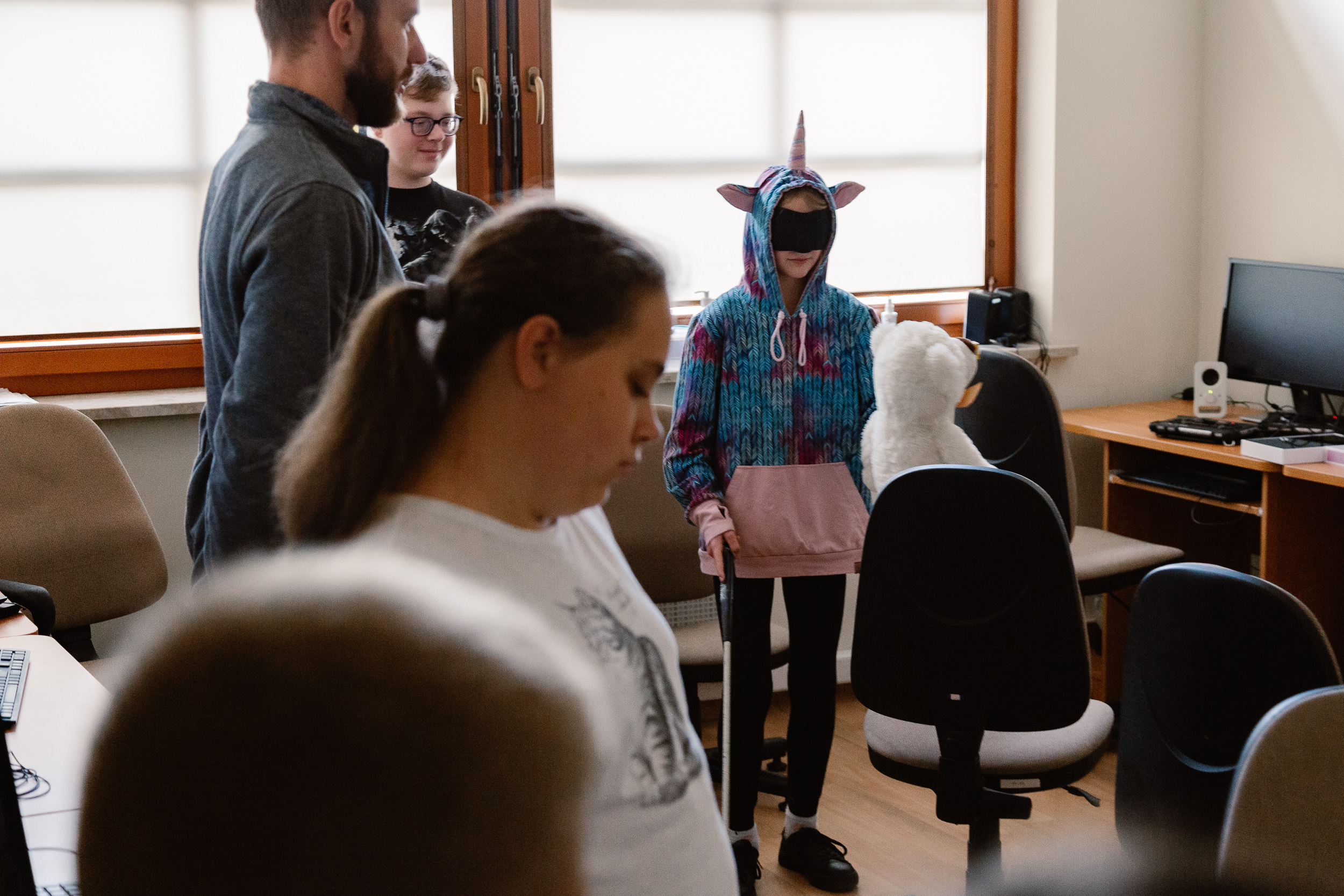 Dziewczynka z opaską i laską szuka maskotki na fotelu