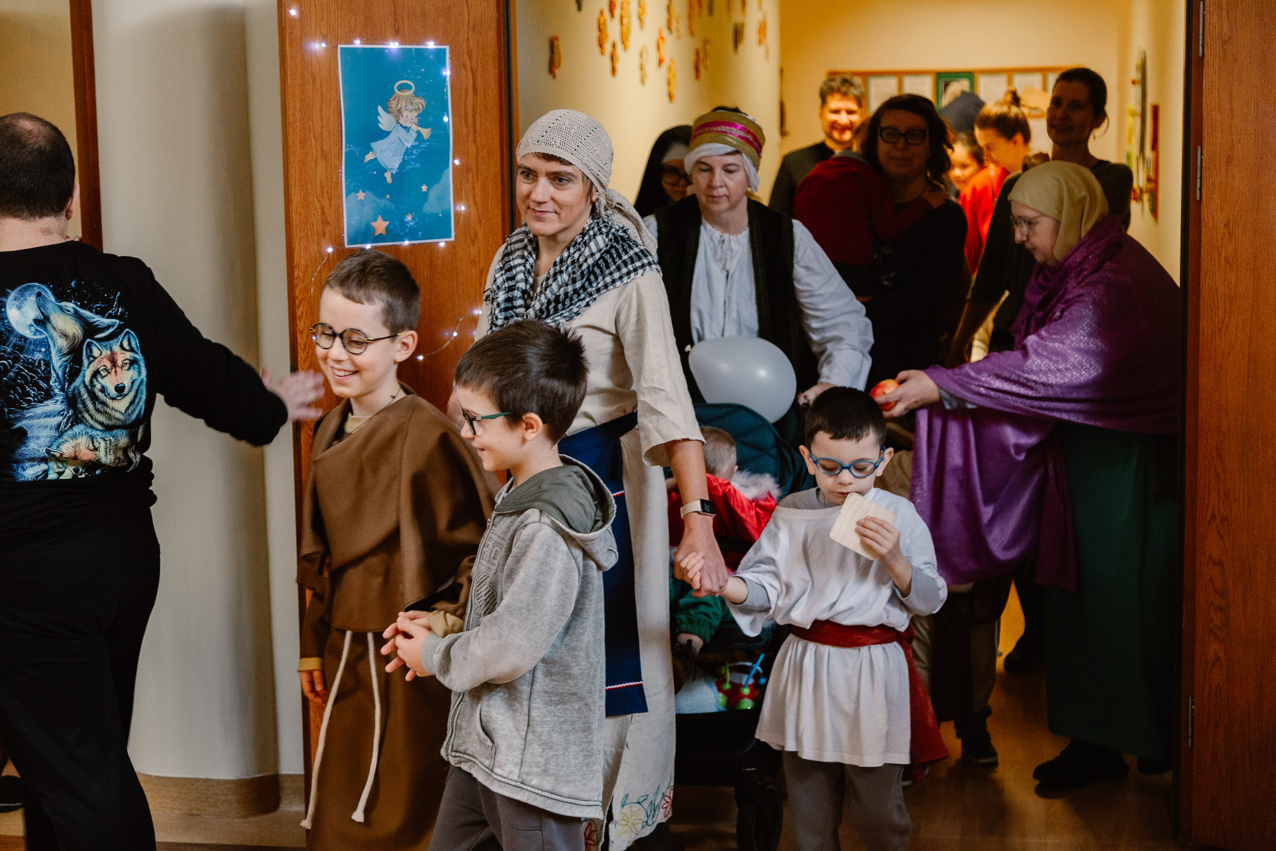 Uczniowie i nauczyciele w przebraniach świętych idą orszakiem po szkole