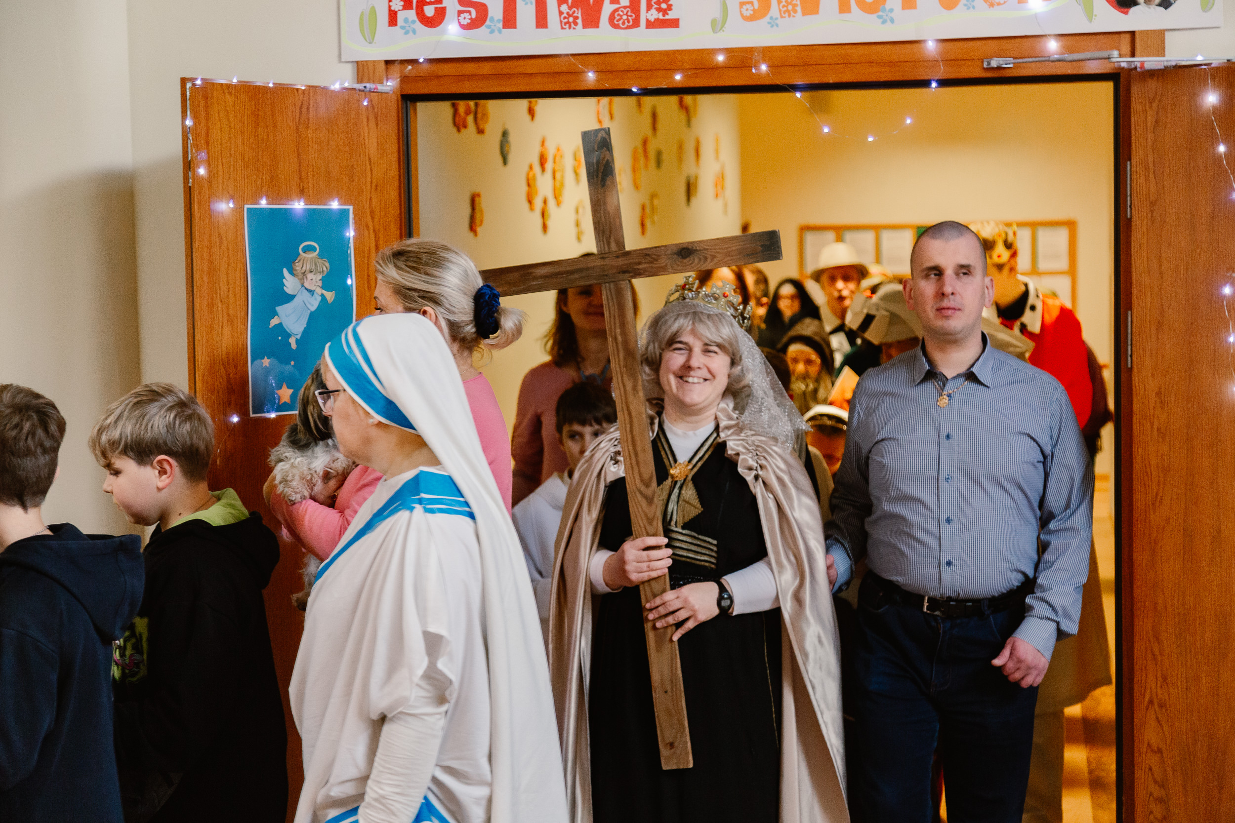 Uczniowie i nauczyciele w przebraniach świętych idą orszakiem po szkole