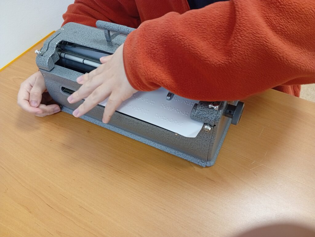 uczeń pisze życzenia na maszynie brajlowskiej