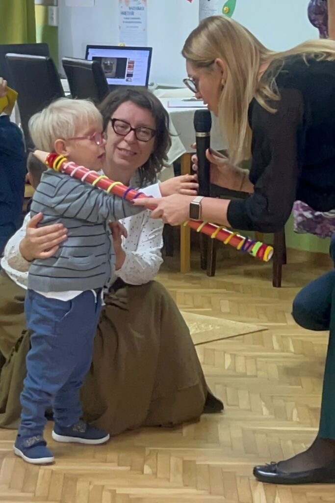Pani Dyrektor pasuje dużą kredką chłopca na przedszkolaka.