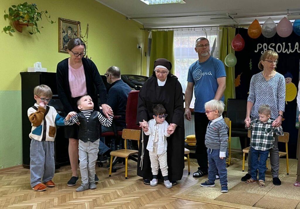 Mali chłopcy z nauczycielami w tle pianino.