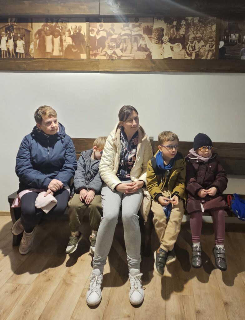 dzieci z nauczycielką siedzą na ławce