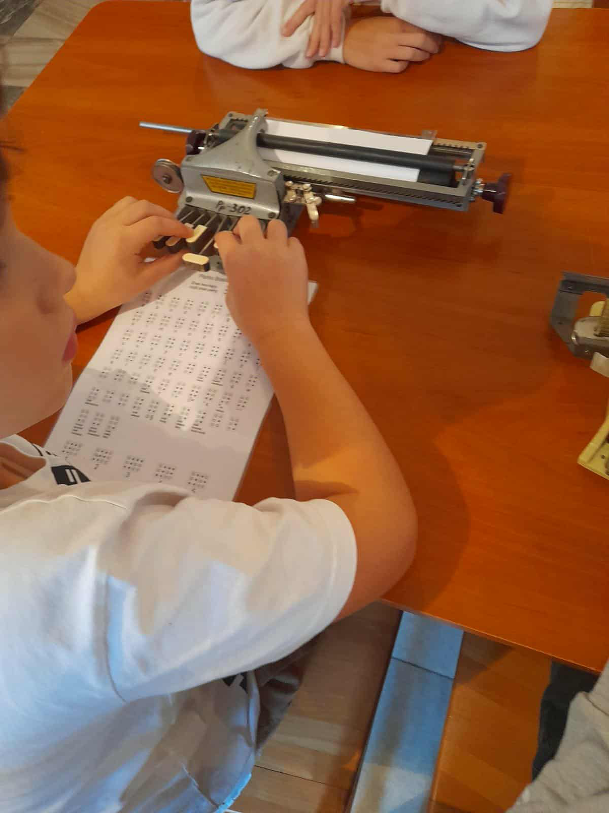 Uczniowie oglądają maszynę brajlowską