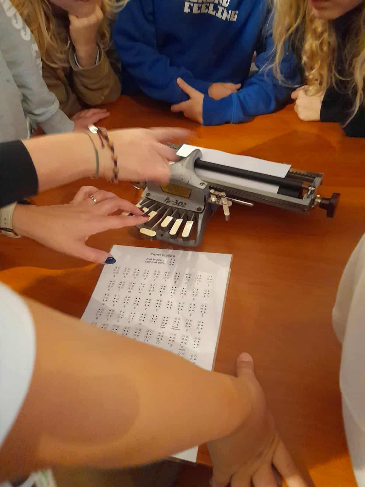 Uczniowie oglądają maszynę brajlowską