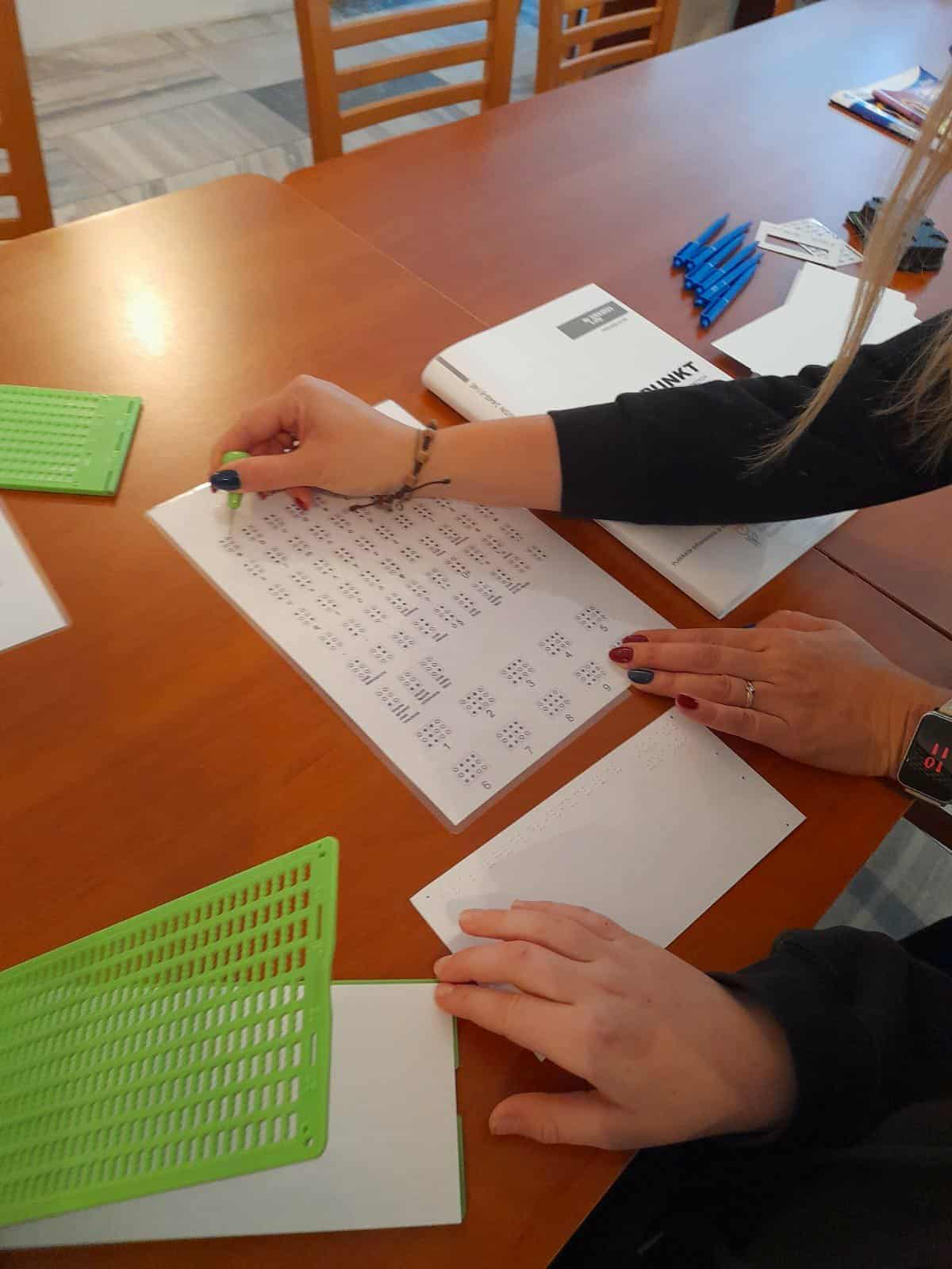 Uczeń pisze na tabliczce brajlowskiej