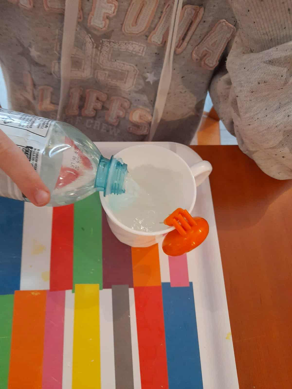 Uczeń próbuje nalać wodę do kubka