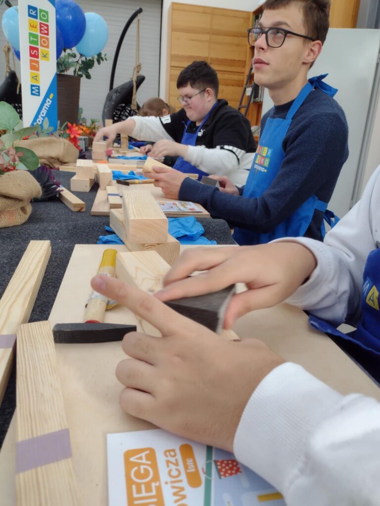 Na zdjęciu uczniowie przy stole dotykają i analizują kształty klocków.