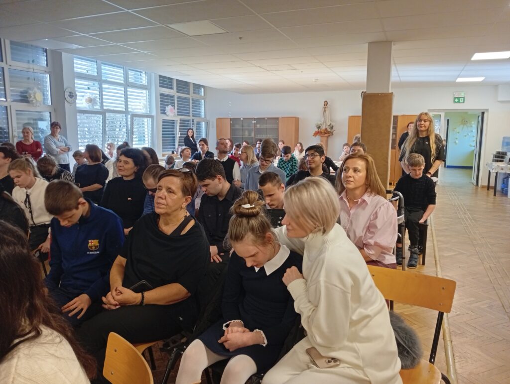 Widzowie siedzą na krzesłach