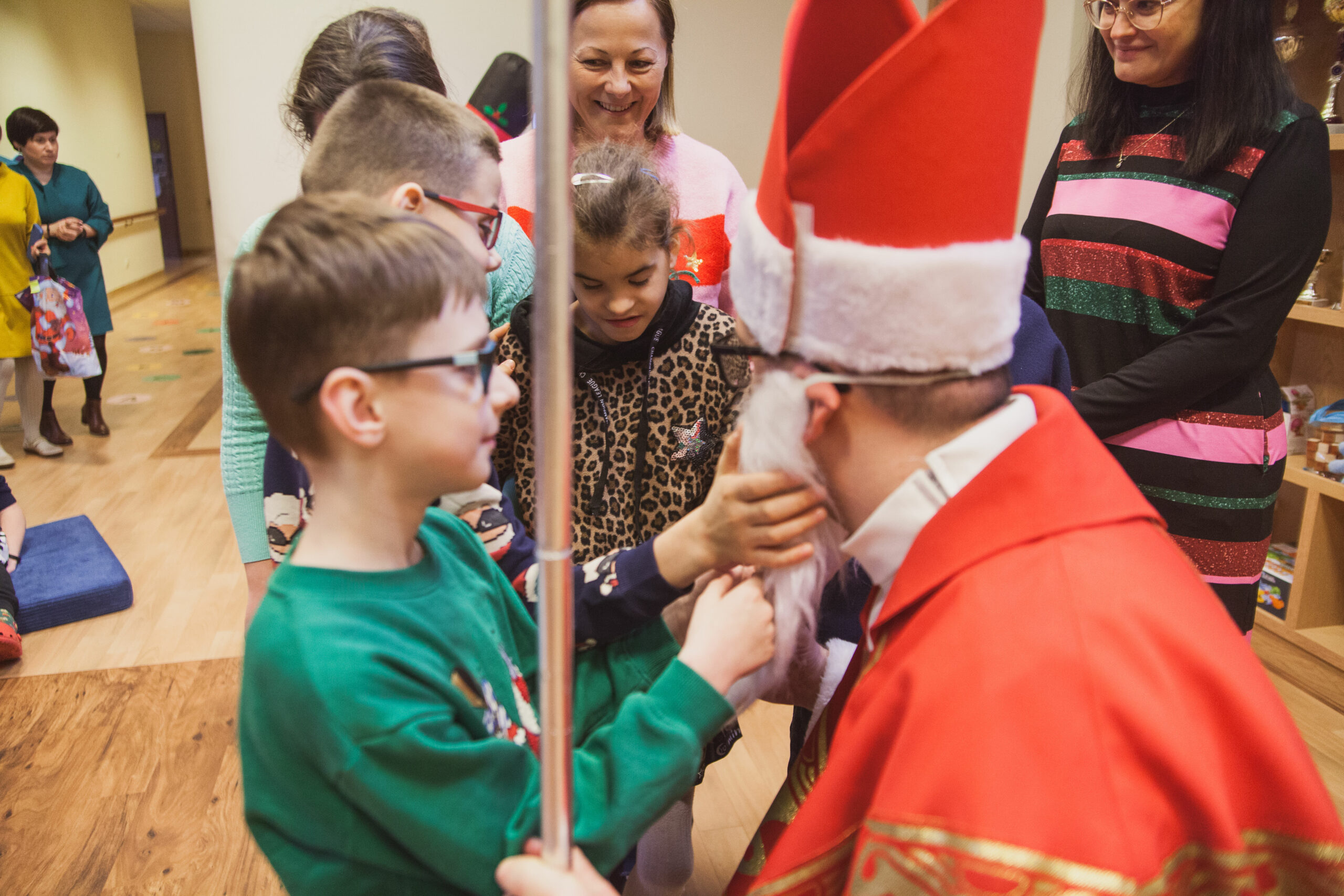 Dzieci dotykają brody Mikołaja.