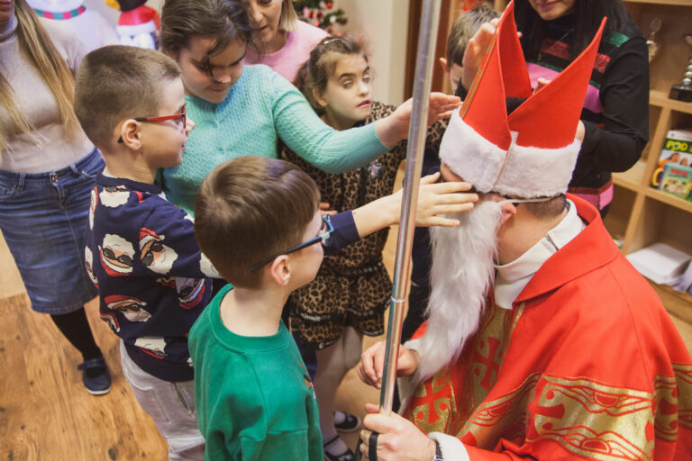 Dzieci dotykają brody Mikołaja.