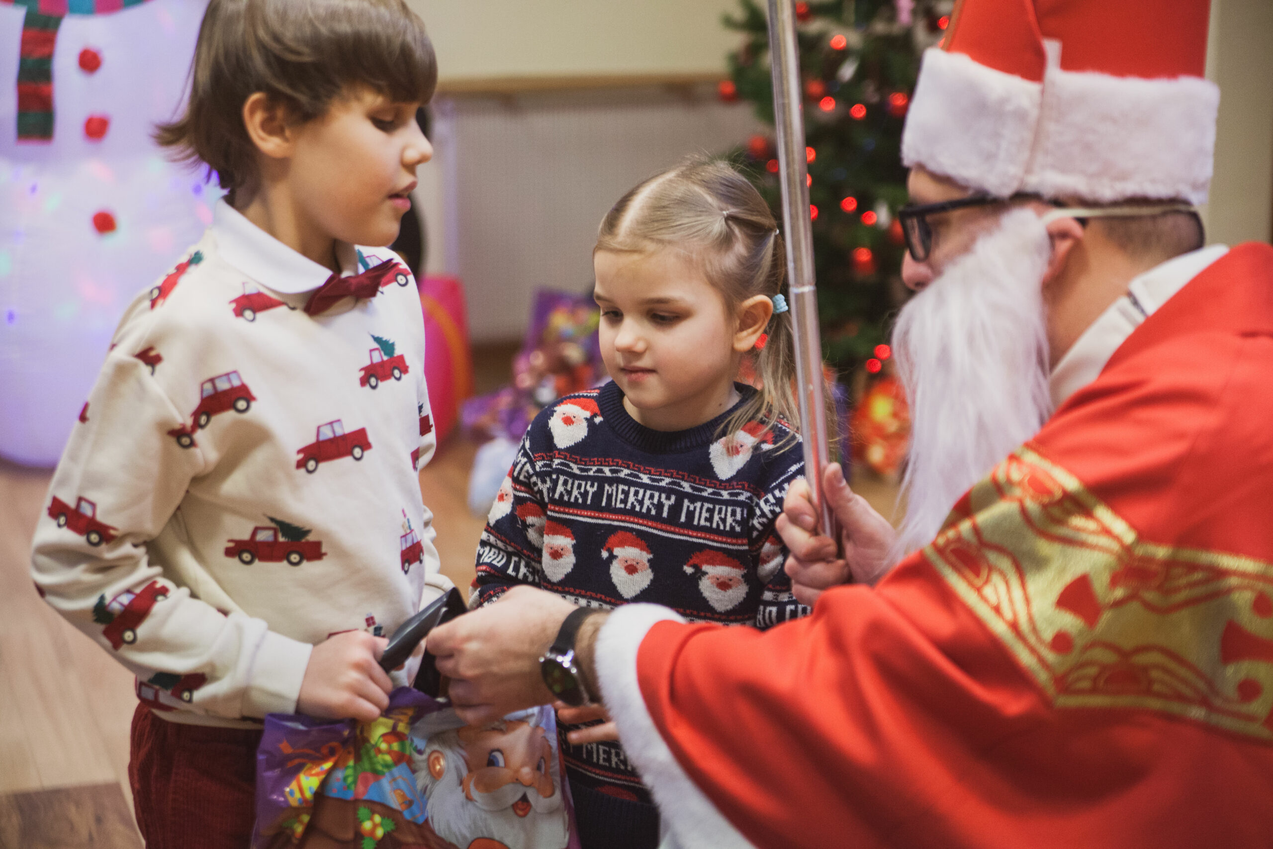 Mikołaj wręcza prezenty dzieciom.