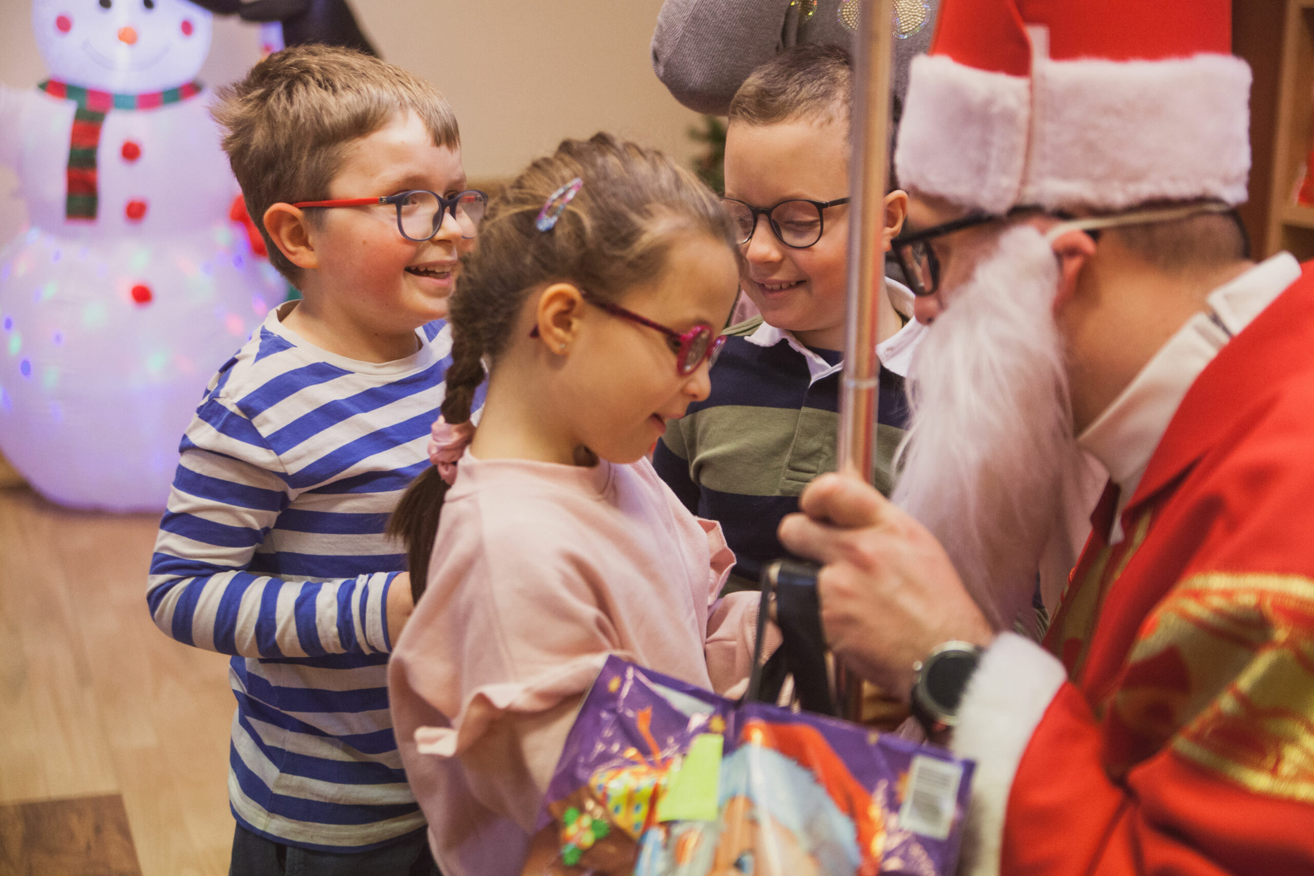 Mikołaj wręcza prezenty dzieciom.