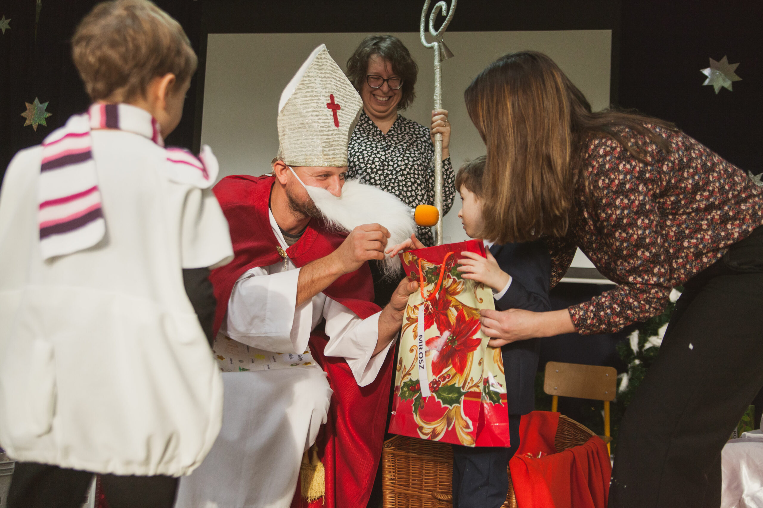 Mikołaj wręcza prezenty dzieciom.