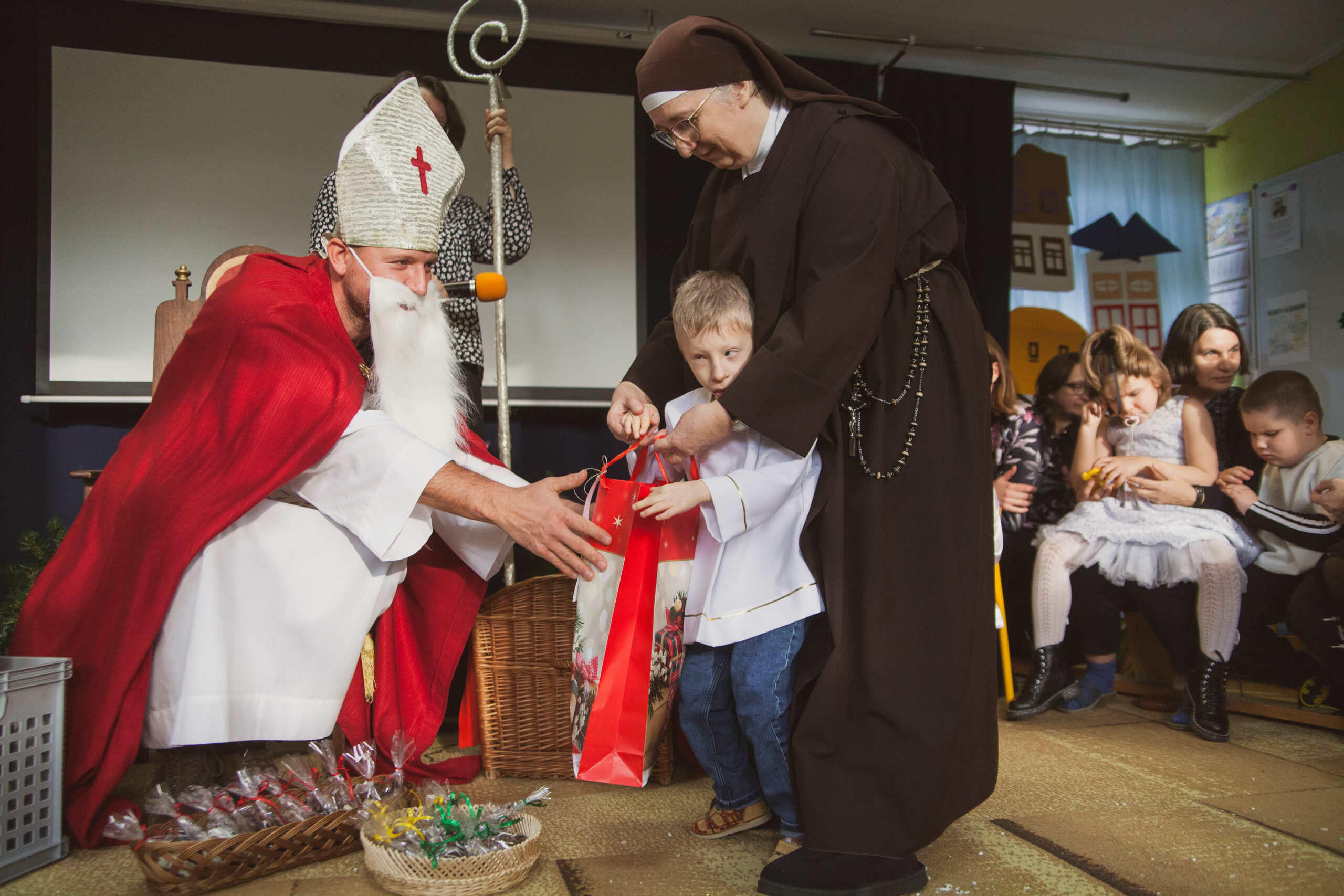 Mikołaj wręcza prezenty dzieciom.