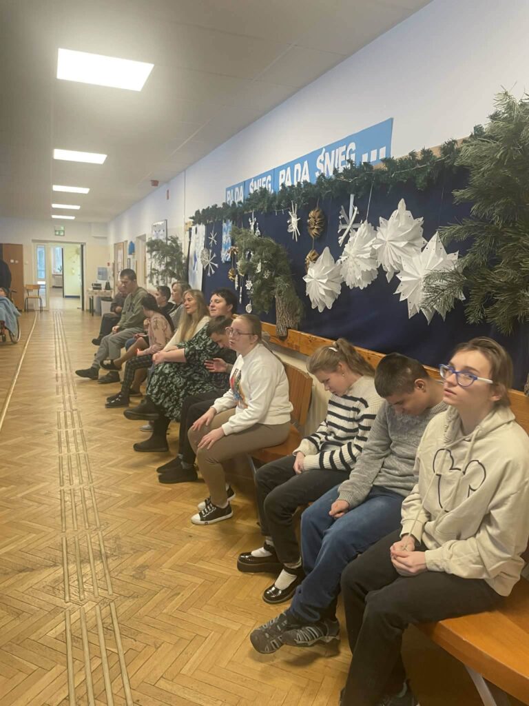 dzieci i nauczyciel siedzą na ławce