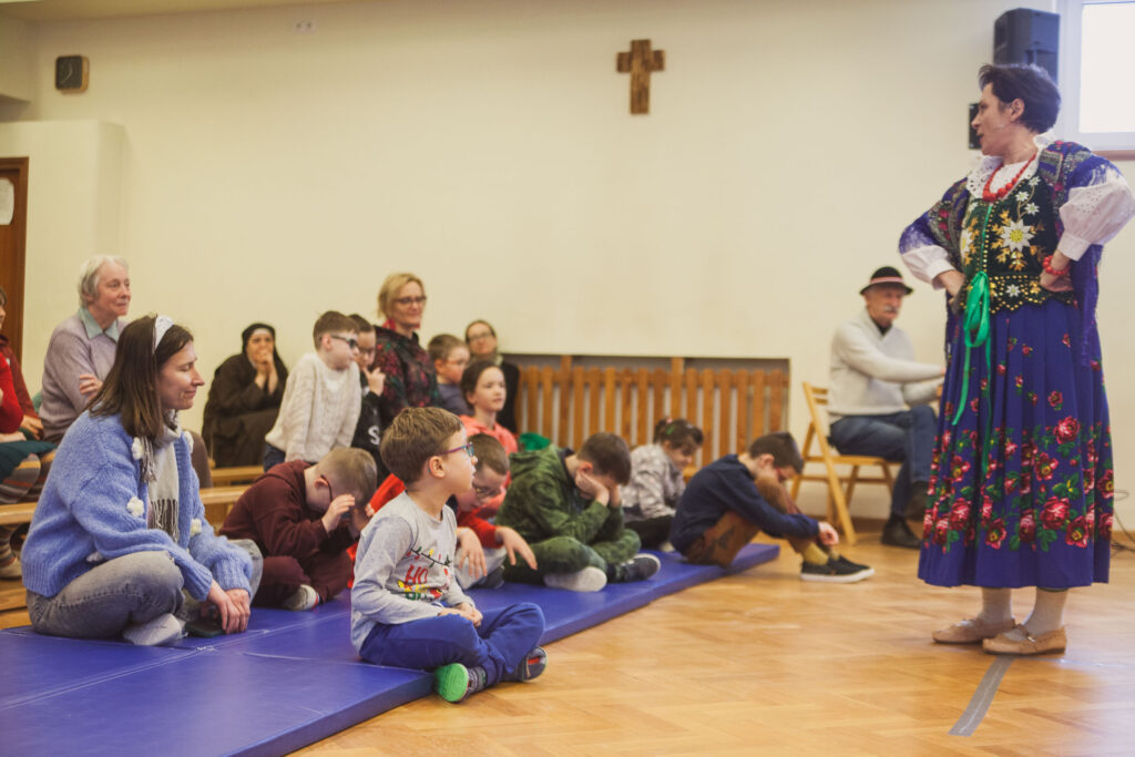 występ w sali gimnastycznej, wykonawcy na scenie i uczniowie na widowni