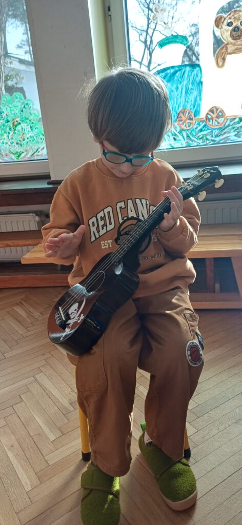 Chłopiec gra na małej gitarze