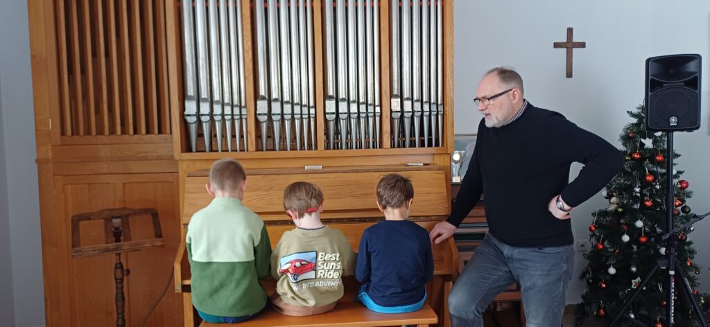 Chłopcy grają na organach obok stoi Pan nauczyciel