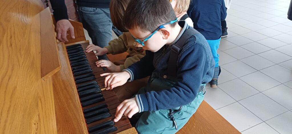 Chłopcy siedzą i grają na organach.