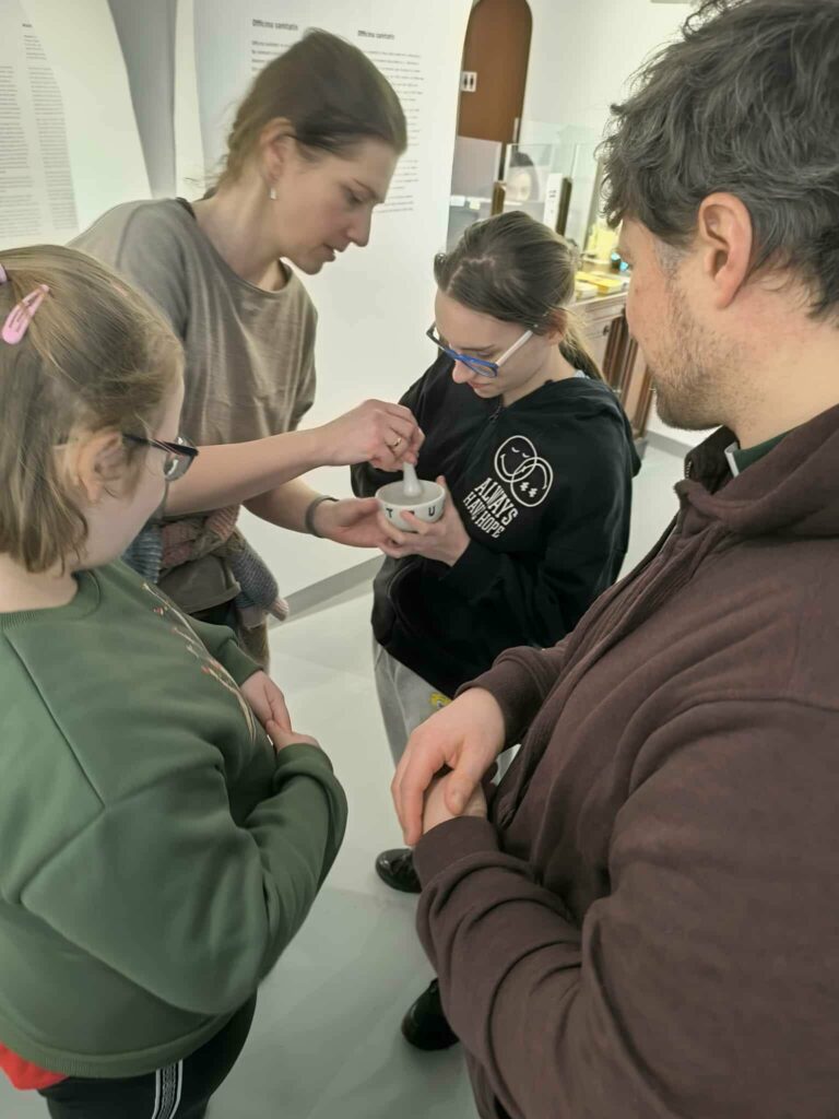 Pani Marta z Jowitą uciera zioła w naczyniu