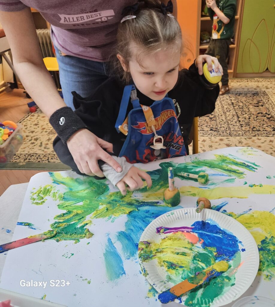 Dziewczynka maluje dłońmi.